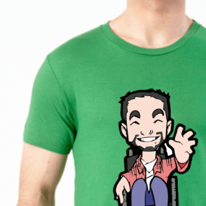 Camiseta manga curta na cor verde no centro o Tom, personagem do blog, homem cadeirante, com barba sorrindo e acenando com a mão esquerda, usa uma camisa de manga longa rosa, outra por dentro branca, calça jeans azul e sapatos pretos.